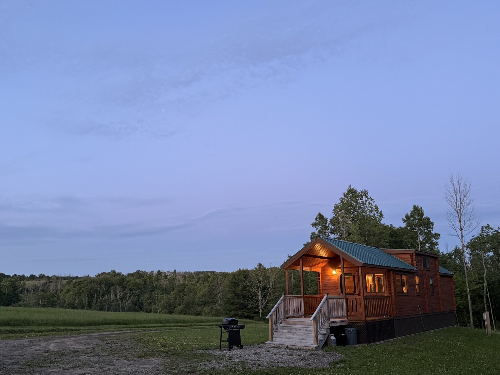 The lit cabin seen across the meadow at nightfall