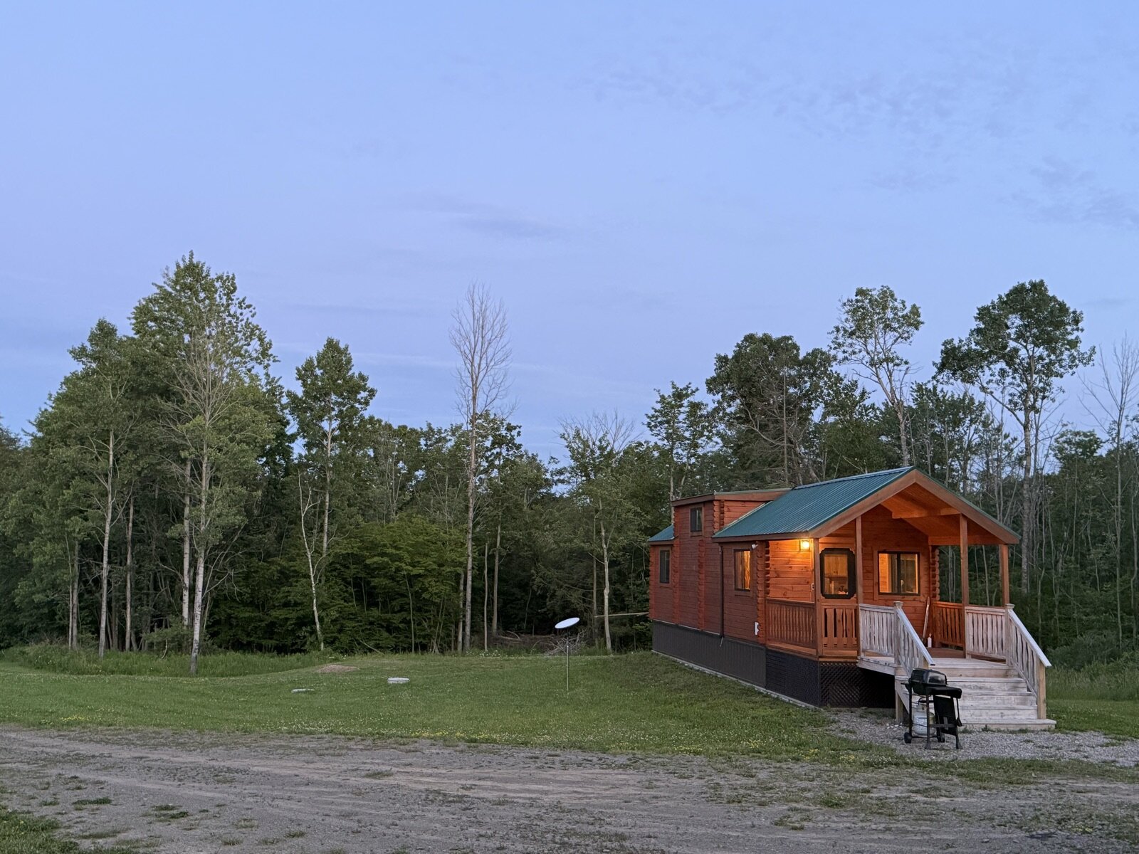 The cabin glowing at dusk against the treeline