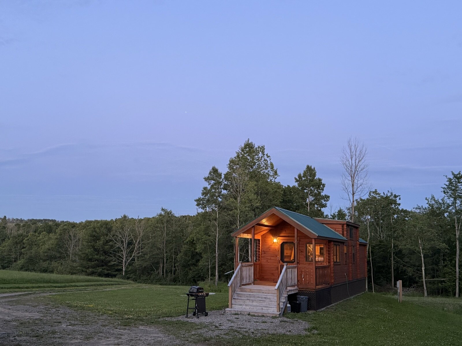 The cabin at dusk with its porch light glowing