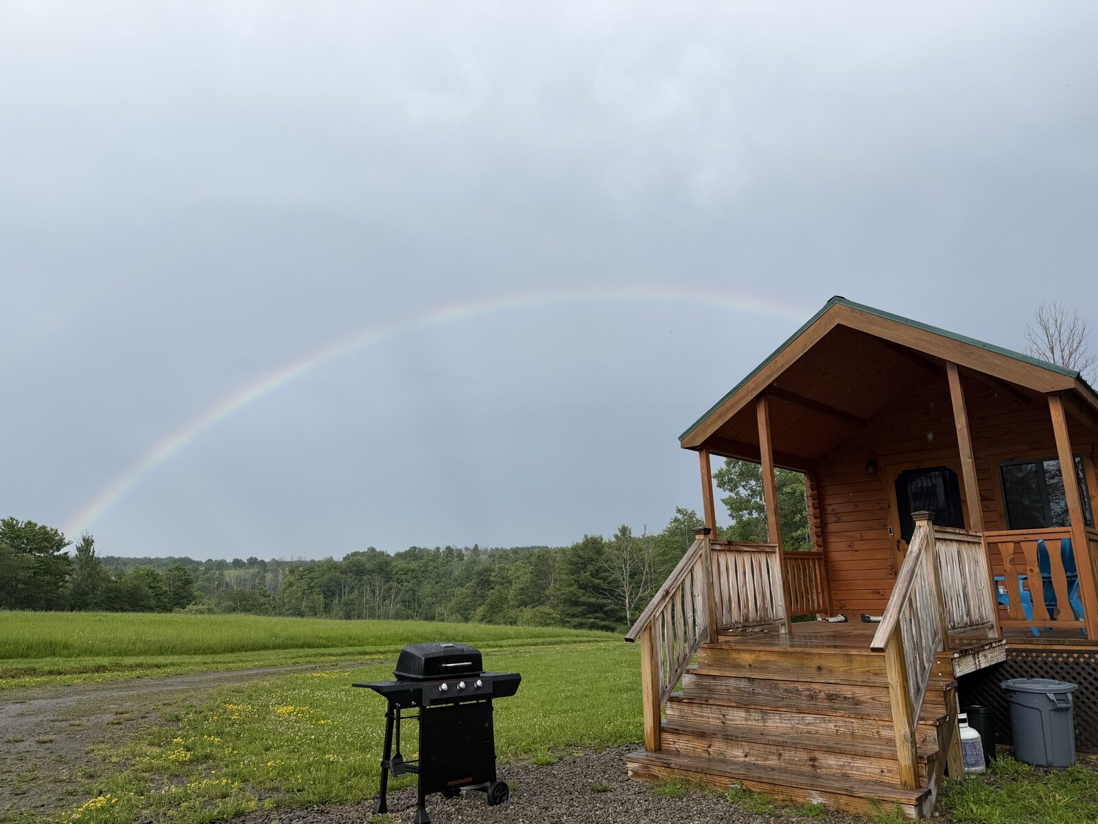 A rainbow arcing over the meadow beside the cabin
