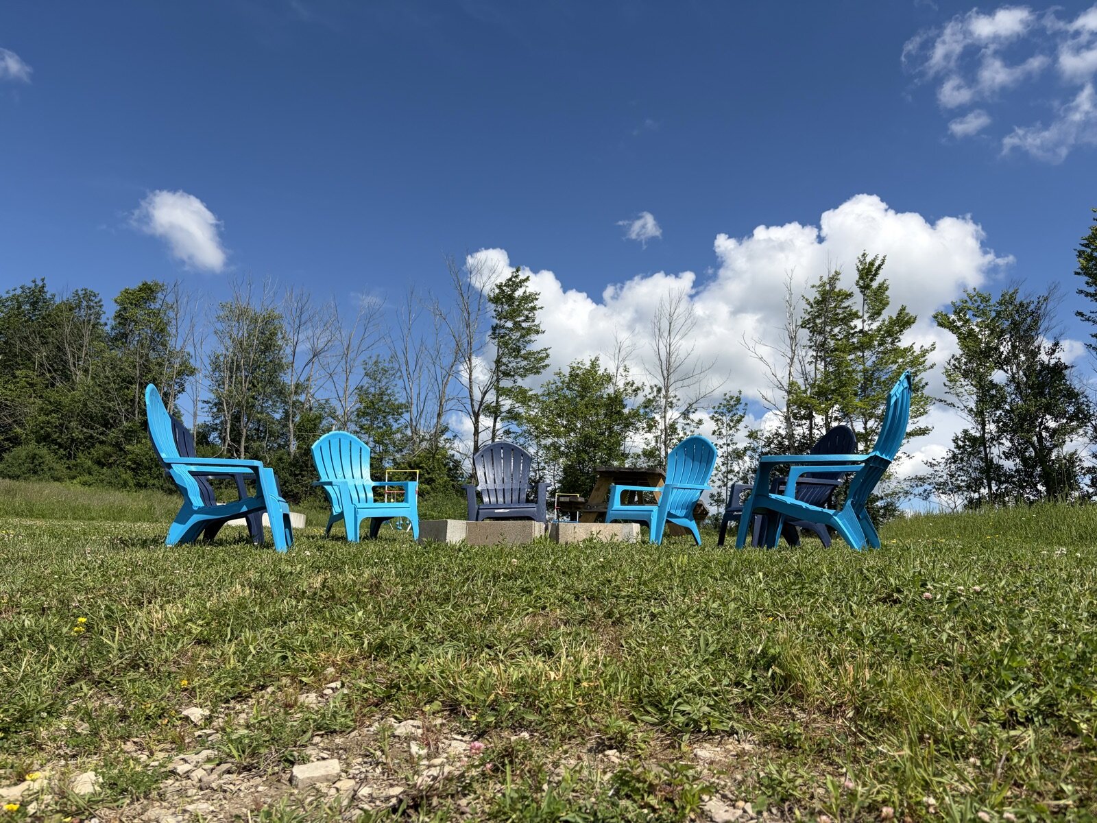 Blue Adirondack chairs on the hilltop under a summer sky