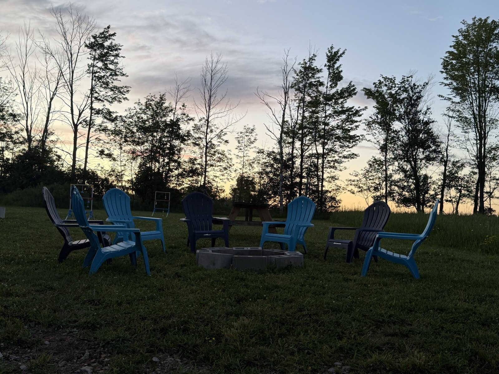 Adirondack chairs circled around the fire pit at sunset